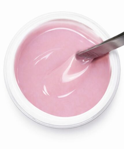 Pink gel nail polish in a clear jar with a metal applicator resting on the rim.