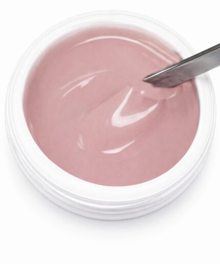 Pink gel nail polish in a white jar with a metal spatula scooping the viscous liquid, ready for application.