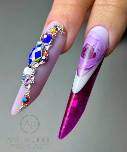 Long lavender stiletto nail with ornate rhinestone embellishment along the base, next to a purple marble-art tip.