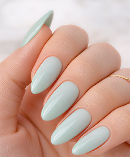 Close-up of a hand showing almond-shaped nails painted pale mint blue with a glossy finish.
