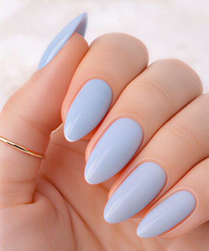 Close-up of a hand with almond-shaped nails painted pale blue and a glossy finish; a thin gold ring sits on the pinky finger.