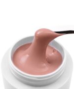 Close-up of a pale pink moisturizer being scooped from a white jar with a black spatula.