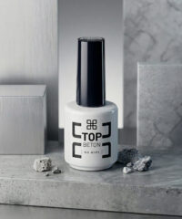 White bottle of Top Beton nail polish with a tall black cap, placed on a gray stone surface.