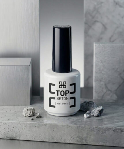 White bottle of Top Beton nail polish with a tall black cap, placed on a gray stone surface.